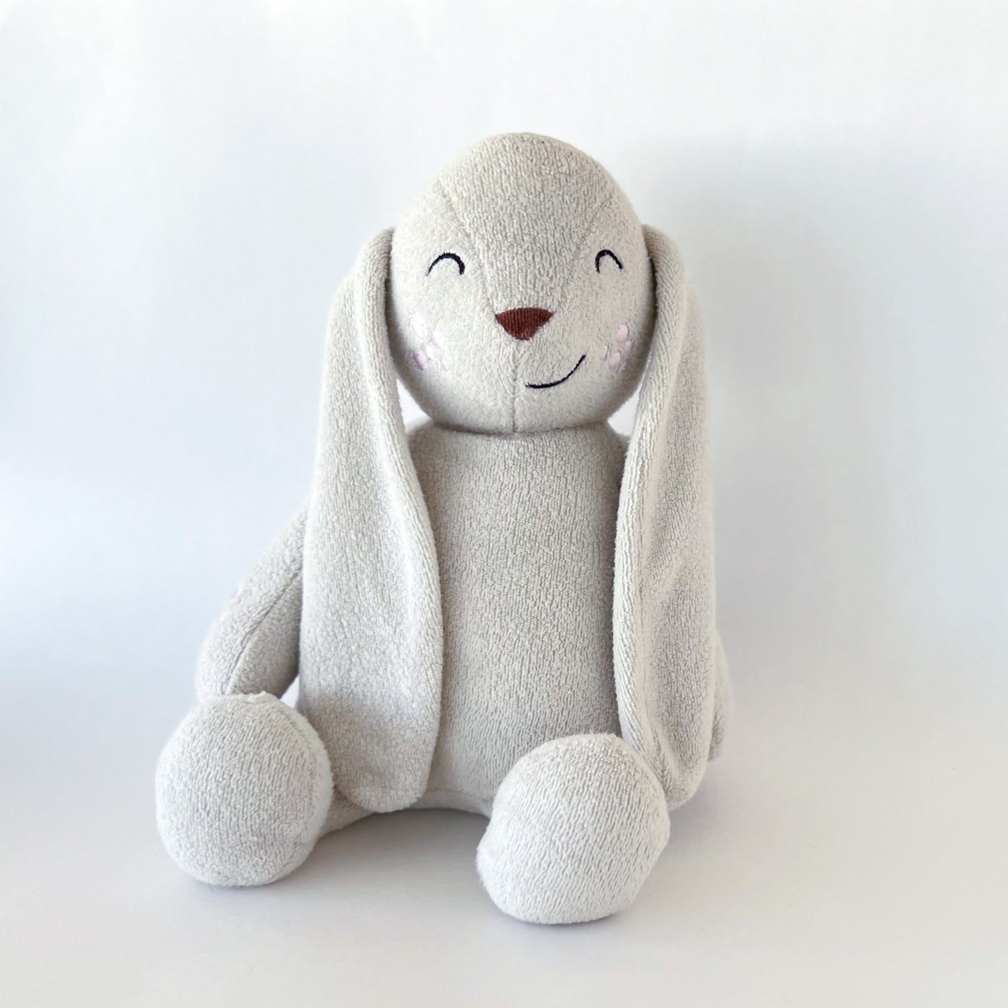 off white stuffed animal bunny with brown nose, embroidered eyes, and embroidered smile, long ears, and embroidered pink patches on cheeks