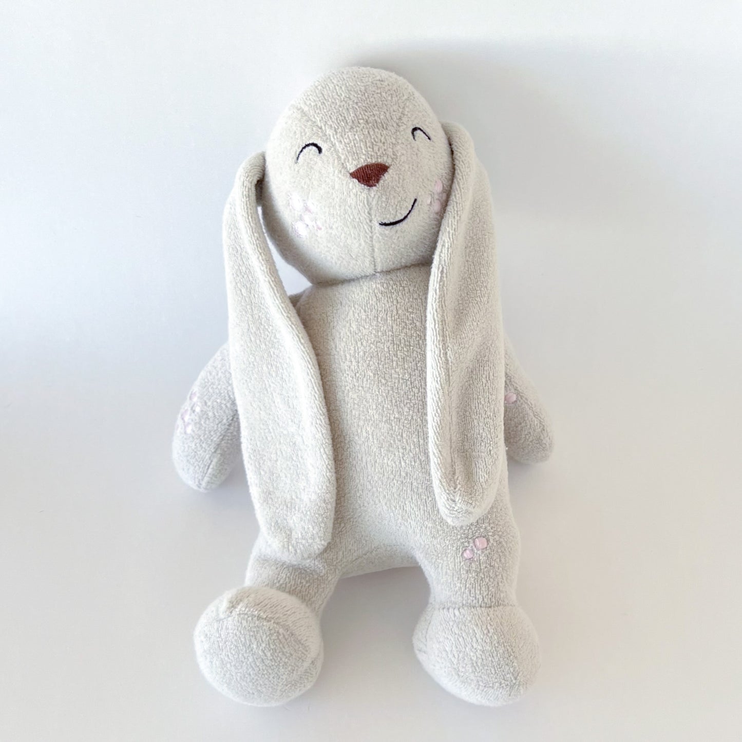 plush toy bunny viewed from a flat lay angle with long ears and embroidered features