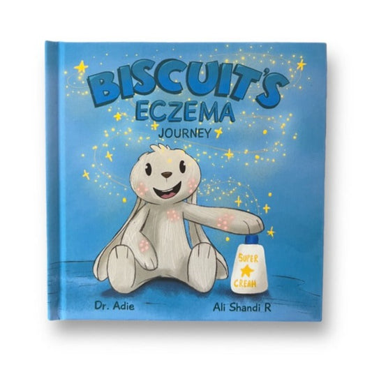 Front of children's blue hardcover book featuring a bunny and cream bottle surrounded by glitter and sparkles titled Biscuit's Eczema Journey