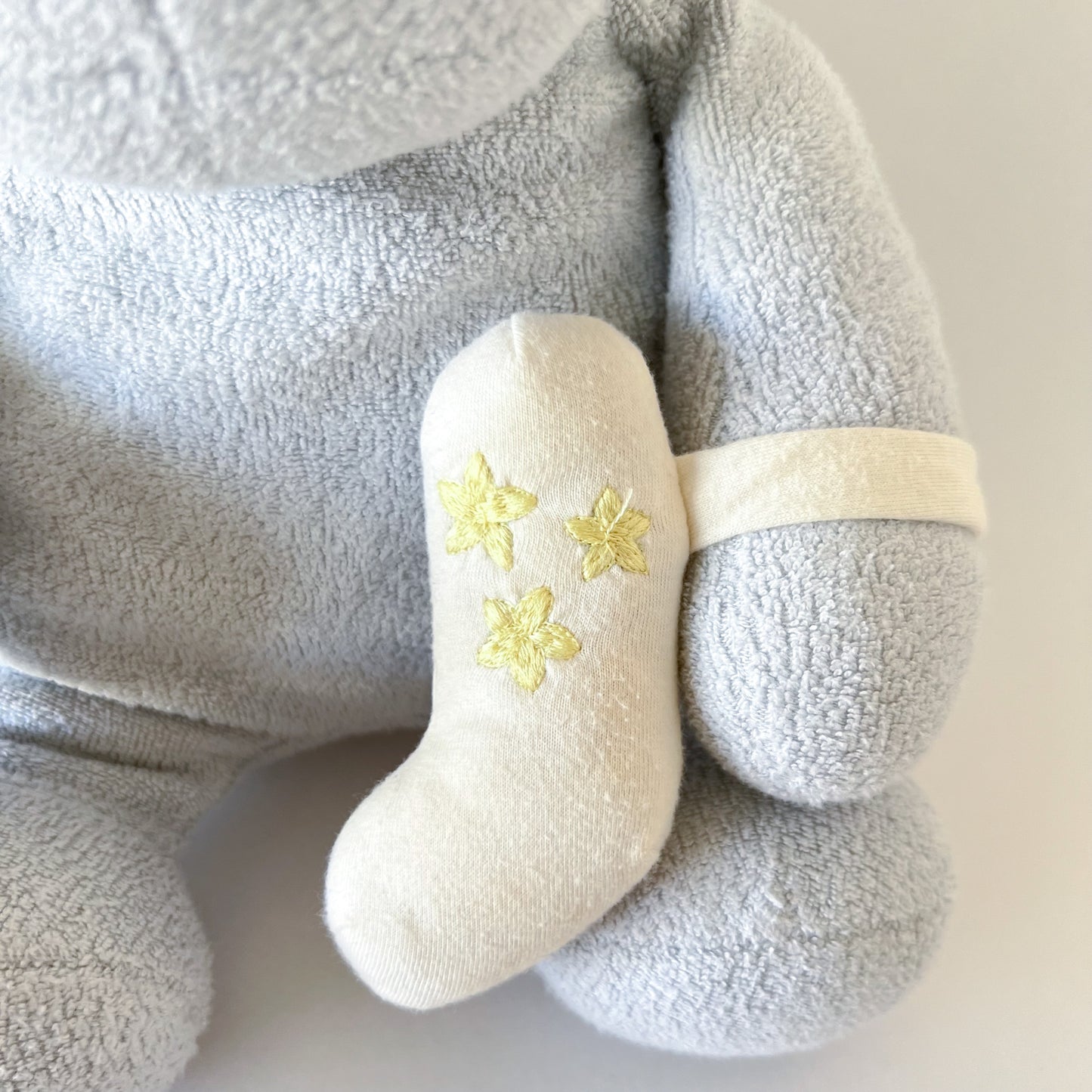 close up image of plush toy inhaler (with embroidered stars on it) strapped to arm of stuffed animal
