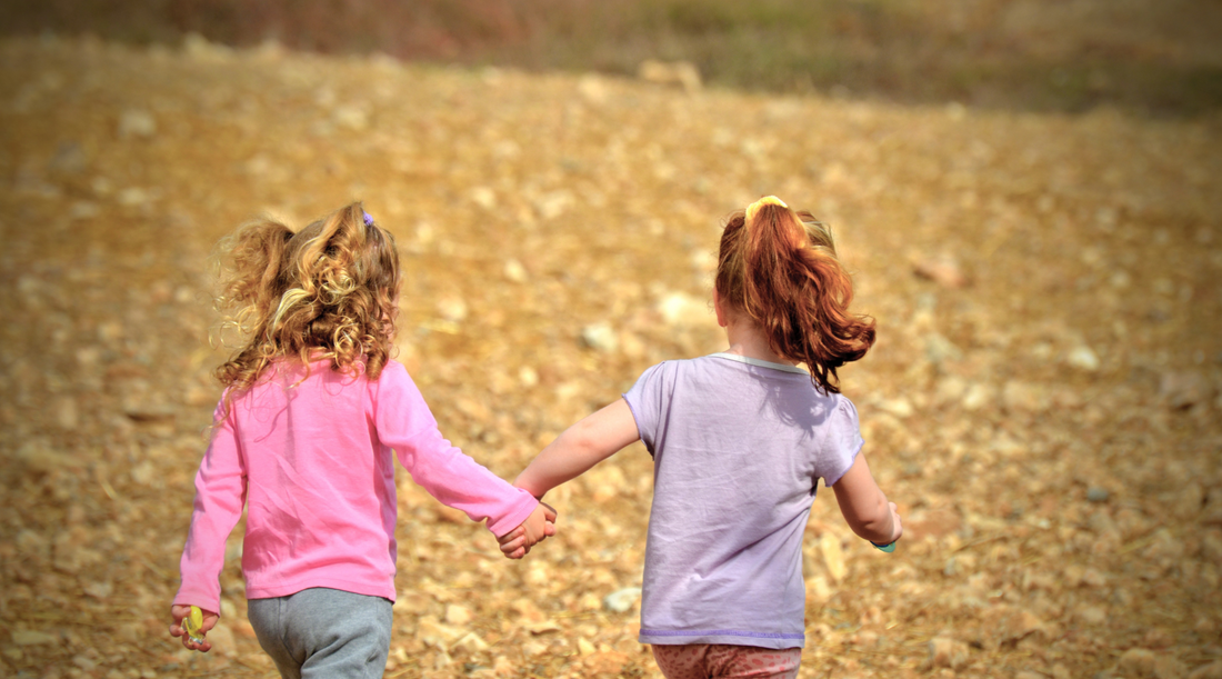 two girls holding hands walking away 