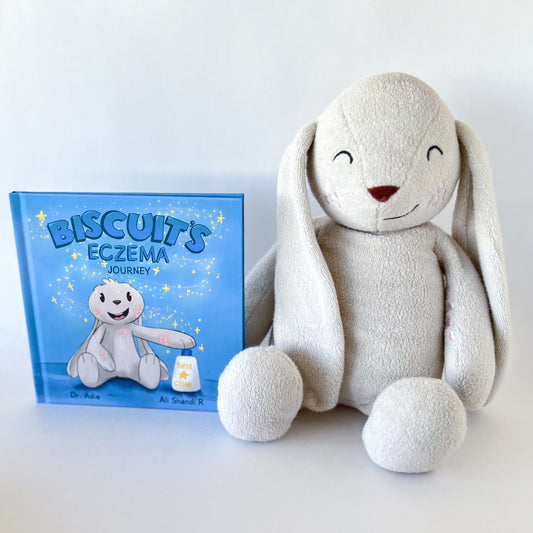 plush toy bunny sitting beside blue hardcover book with a bunny on it titled Biscuit's Eczema Journey