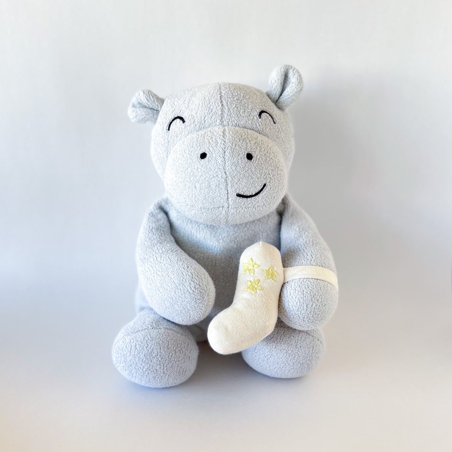 blue stuffed animal hippo with cream colored inhaler strapped to arm