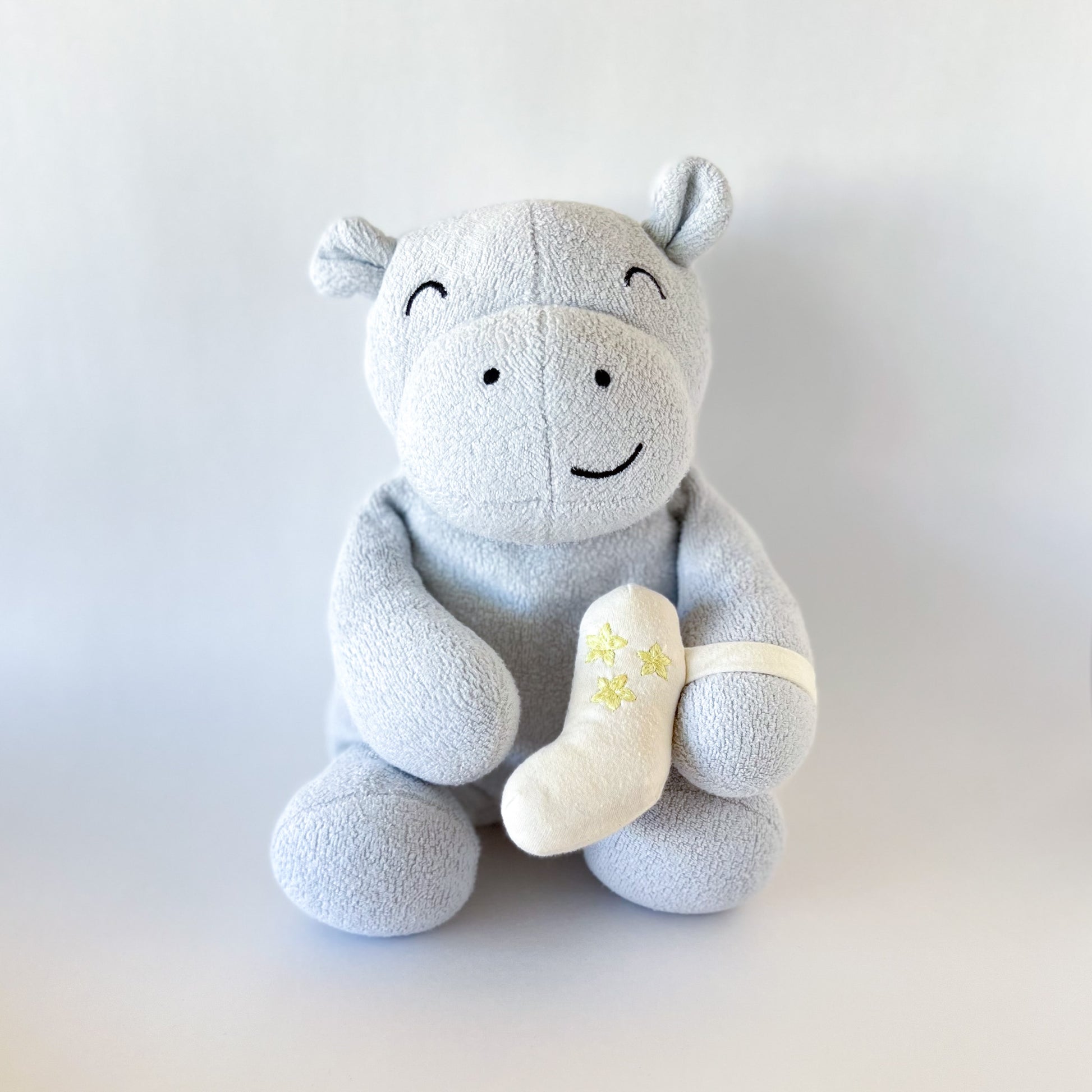 blue stuffed animal hippo with cream colored inhaler strapped to arm